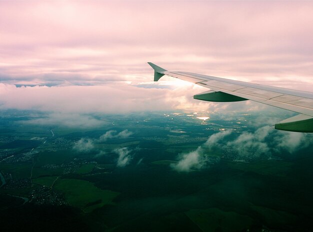 Foto imagem recortada de um avião voando sobre uma paisagem nublada