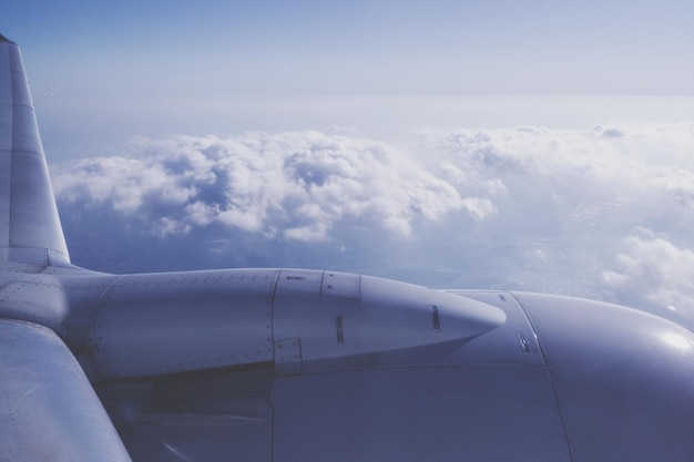 Foto imagem recortada de um avião voando sobre uma paisagem nublada