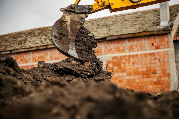 Imagem recortada de um balde de bulldozer derramando solo em uma pilha no local