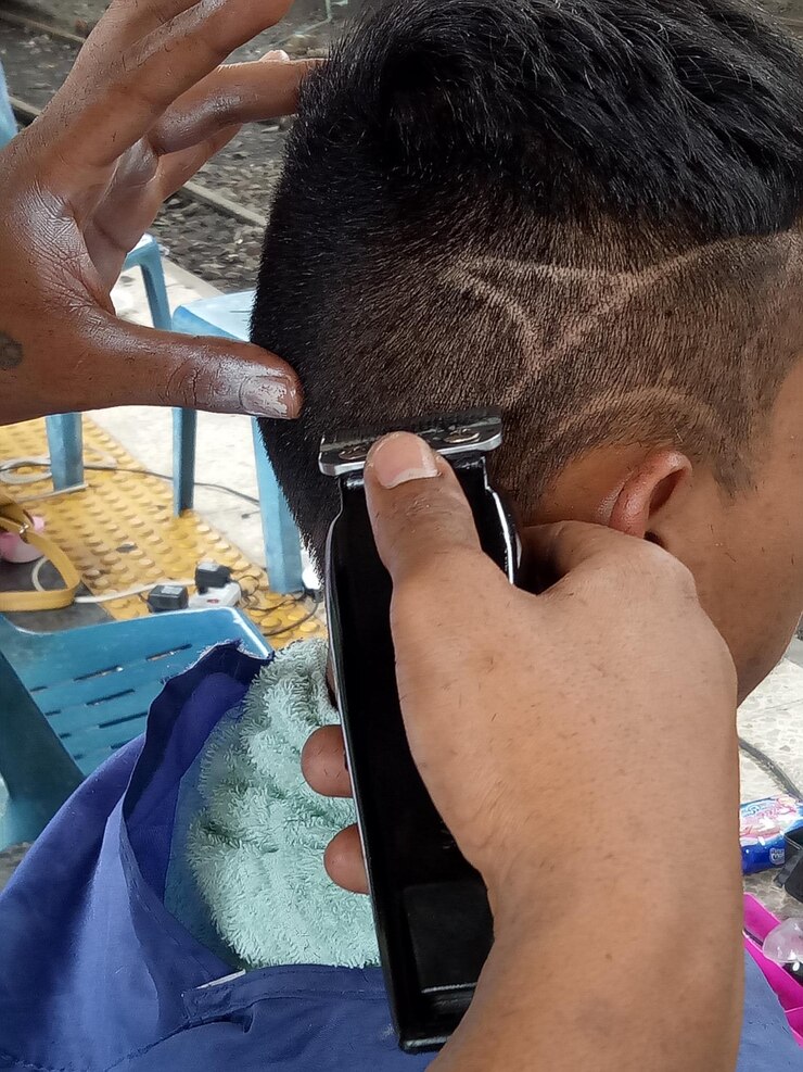 Foto imagem recortada de um barbeiro cortando o cabelo de um cliente com uma navalha elétrica