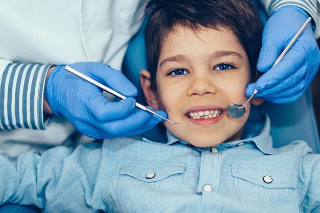 Foto imagem recortada de um dentista examinando um menino na clínica