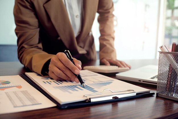 Imagem recortada de um empresário apontando para um gráfico na mesa no escritório