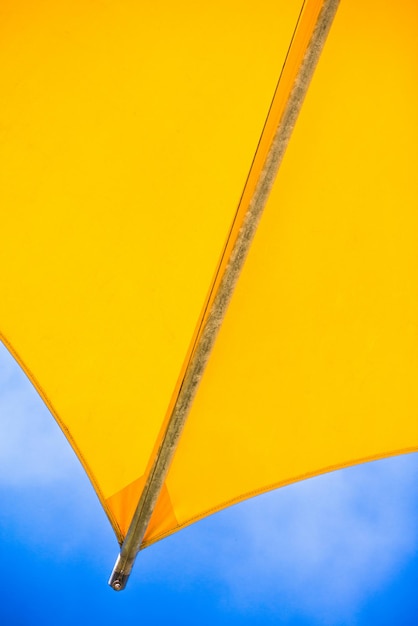 Foto imagem recortada de um guarda-chuva amarelo contra o céu