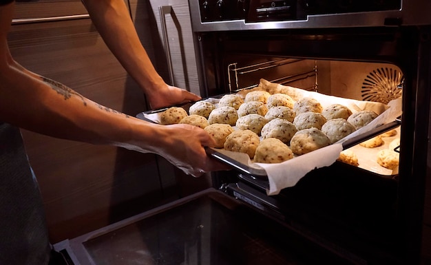 Imagem recortada de um homem colocando uma bandeja no forno