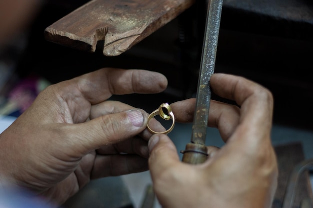 Foto imagem recortada de um joalheiro moldando um anel com rasp na oficina