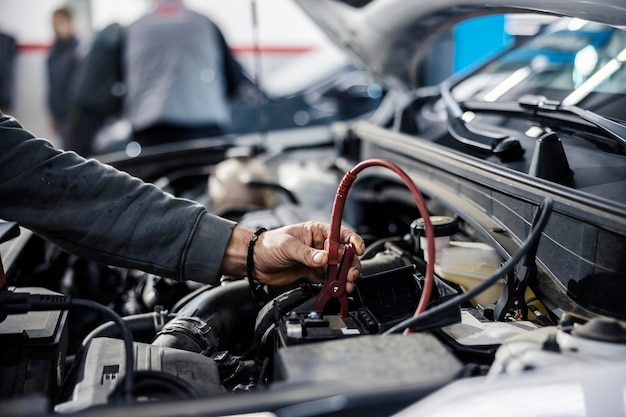 Imagem recortada de um mecânico fazendo diagnósticos de bateria de carro