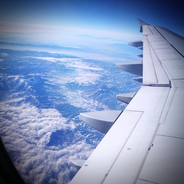 Foto imagem recortada de uma asa de avião voando sobre montanhas