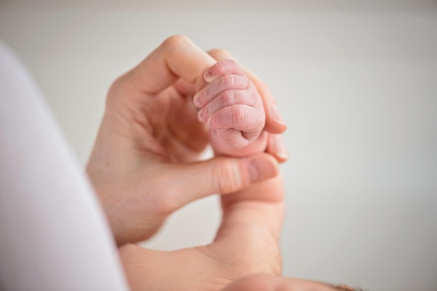 Imagem recortada de uma mãe segurando a mão do bebê