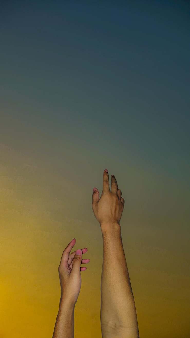Foto imagem recortada de uma mão contra um céu claro durante o pôr-do-sol