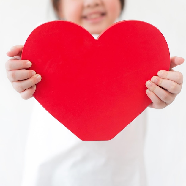 Foto imagem recortada de uma menina segurando uma forma de coração vermelho contra um fundo branco
