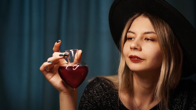 Imagem recortada de uma mulher segurando um frasco de vidro em forma de coração com poção do amor