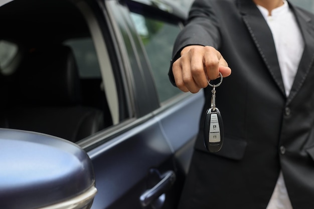 Imagem recortada de vendedor de carros entregando suas novas chaves de carro, concessionária e conceito de vendas.