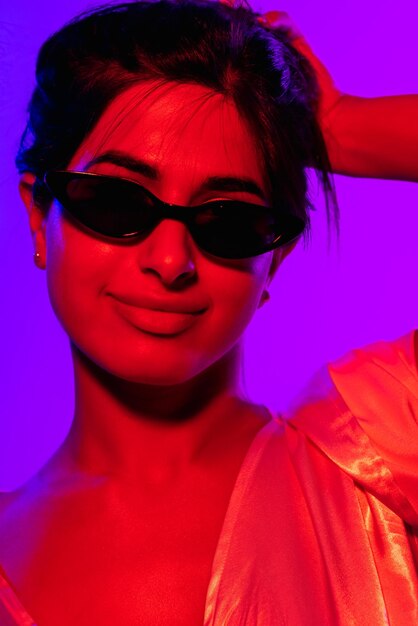 Imagem recortada em close de uma jovem linda em óculos de sol pretos da moda isolados sobre roxo neon