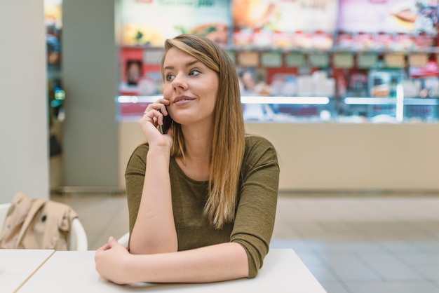 Imagem sincera de uma jovem mulher falando ao telefone em um café.