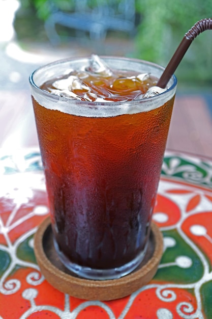 Foto imagem vertical de um copo de café gelado em uma mesa de ladrilhos coloridos