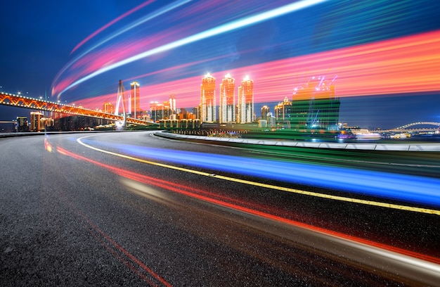 Imagen abstracta de movimiento borroso de automóviles en la carretera de la ciudad por la noche, arquitectura urbana moderna en Chongqing, China