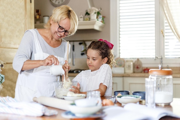 Imagen de una abuela y una nieta adorable que se preparan juntas en la cocina, con los ingredientes en la mesa.