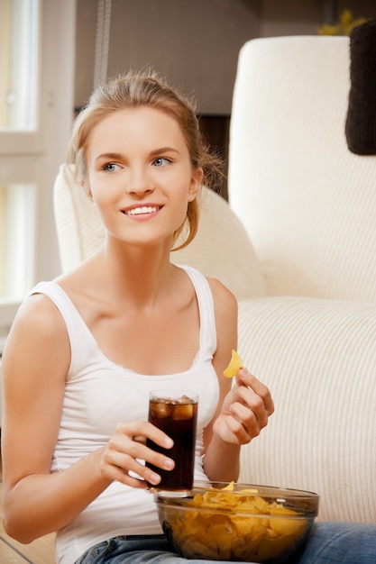 Imagen de una adolescente sonriente con patatas fritas y coca cola