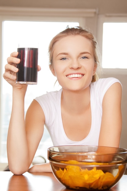 Imagen de una adolescente sonriente con patatas fritas y coca cola