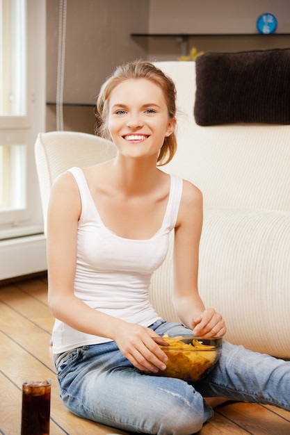 Imagen de una adolescente sonriente con patatas fritas y coca cola