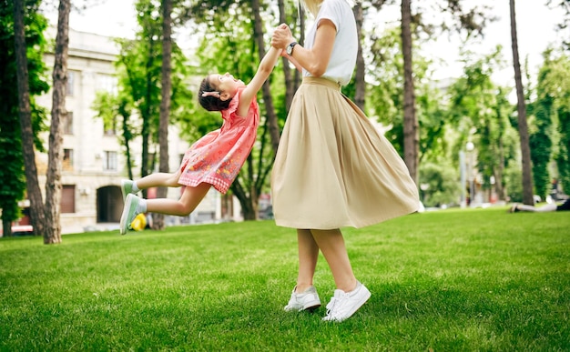 Imagen al aire libre de una hija feliz jugando con su madre en el parque Madre amorosa y su hijo girando y disfrutando el tiempo juntos Mamá y niña divirtiéndose afuera Feliz día de las madres