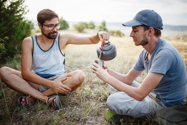 Imagen al aire libre del joven explorador bebiendo bebida caliente