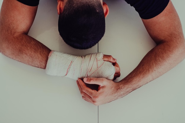 Foto imagen al revés de un hombre deprimido con la mano envuelta en una venda por la pared