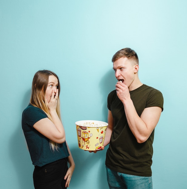 La imagen de amigos felices aisló sostener la película del reloj de la palomitas de maíz.