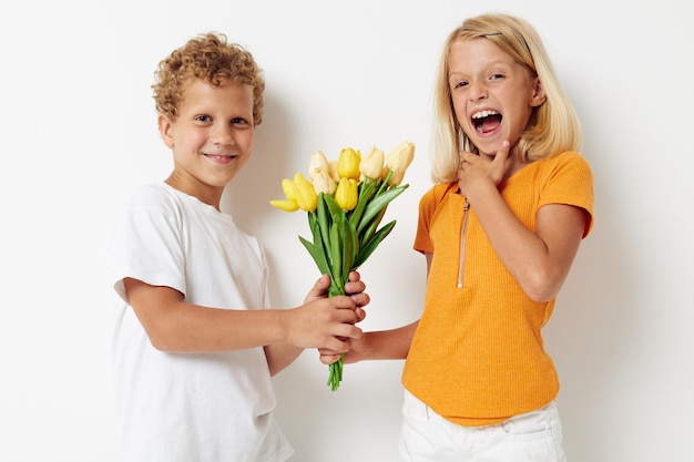 Imagen de amistad positiva de vacaciones de niño y niña con un regalo Flores amarillas fondo claro