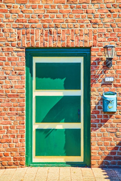 Imagen de la antigua puerta verde y amarilla de estilo holandés en ladrillo rojo