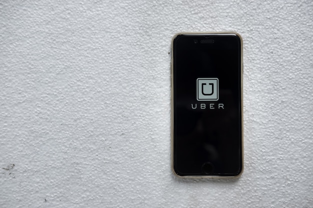 Foto imagen de la aplicación de uber mostrando en un smarthphone en la caja de espuma, uber es la red de transporte basada en app smartphone.