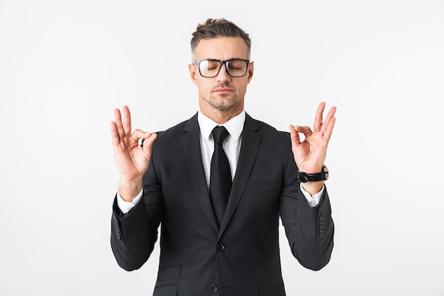 Imagen de un apuesto hombre de negocios aislado sobre pared blanca meditar.