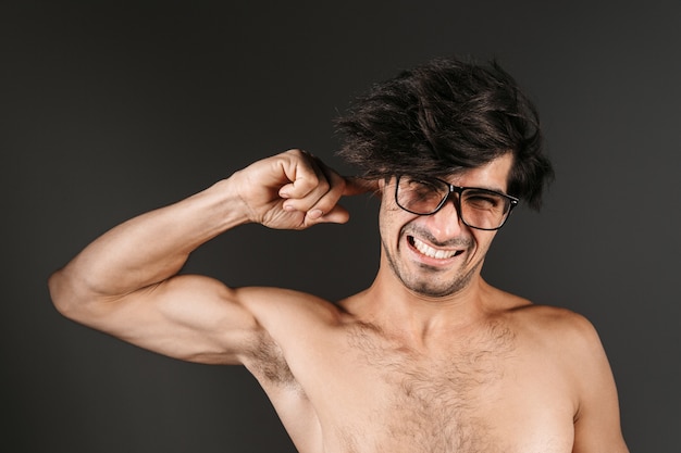 Imagen de un apuesto joven desnudo posando aislados con gafas que cubren la oreja.