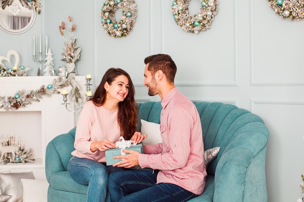 Imagen de un apuesto joven enamorado presentando un regalo de Navidad a su prometida Adorable mujer sonriente mirando a su pareja con felicidad