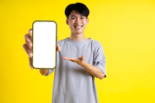 Imagen de un apuesto joven usando su teléfono y posando sobre un fondo amarillo