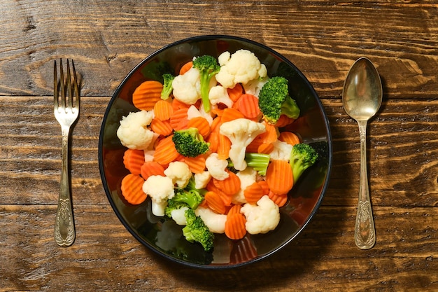 Foto imagen desde arriba de un plato lleno de vegetales saludables en una mesa de madera marrón