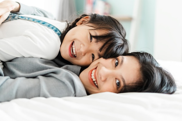 Imagen asiática de madre e hija en la cama