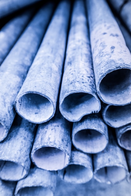 Imagen de baja profundidad de campo de la pila de tubos de metal en tono de sombra azul. Forma de tubo de hierro redondeado.