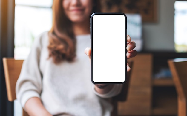 Imagen de una bella mujer asiática sosteniendo y mostrando un teléfono móvil con pantalla en blanco