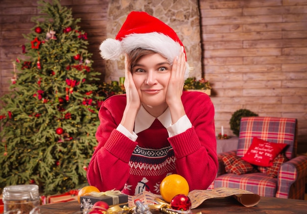 Imagen de una bella mujer con ropa navideña. Ella está empaquetando los regalos de Año Nuevo en una casa de campo. Concepto de vacaciones. Técnica mixta