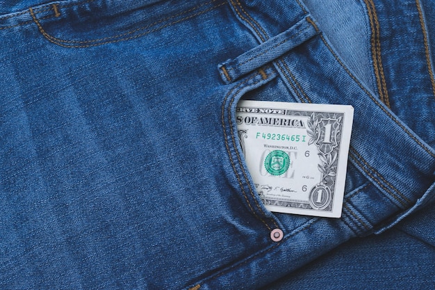 Una imagen de un billete de un dólar estadounidense que sobresale del bolsillo de los pantalones vaqueros azules
