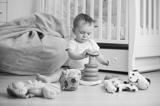 Imagen en blanco y negro de adorable bebé jugando en el piso