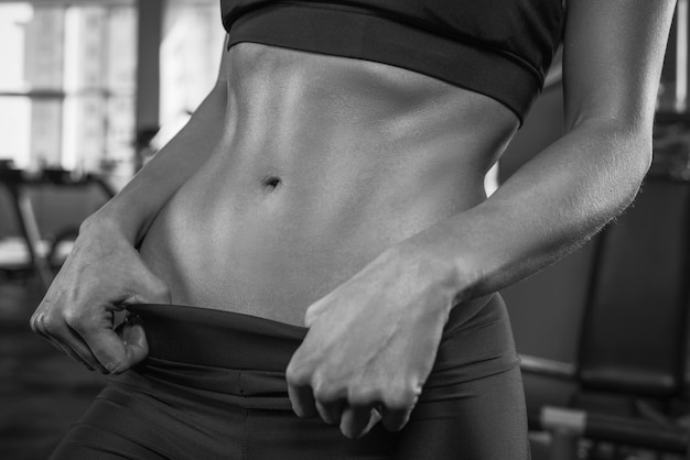 Imagen en blanco y negro de una joven atlética en el gimnasio. Concepto de fitness y culturismo. Deportes y motivación. Técnica mixta
