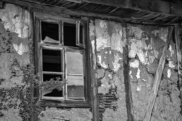 Imagen en blanco y negro de ventanas rotas casa rústica abandonada