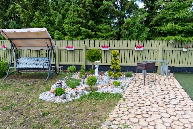 Imagen de un bonito patio trasero en su propia casa en verano Flores, árboles y estatuillas con un diseño acogedor