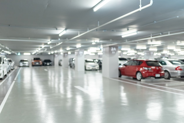 Foto imagen borrosa abstracta de muchos coches en el interior del garaje de estacionamiento en grandes almacenes o centro comercial, edificio industrial para el fondo