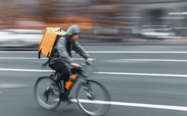Imagen borrosa de movimiento de enfoque suave de un mensajero de entrega de alimentos entrega alimentos. Tiempo de exposición prolongado. Imagen de desenfoque de movimiento