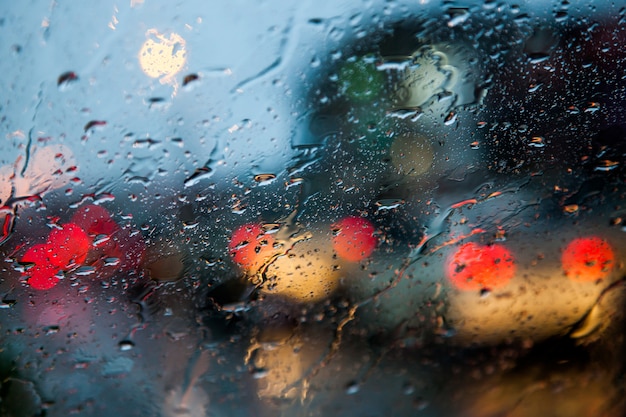 imagen borrosa de la vista de tráfico a través del parabrisas de un coche cubierto de lluvia