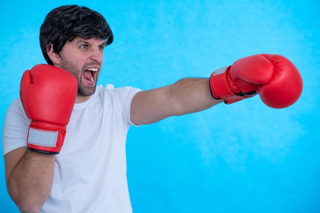 Imagen de un boxeador joven fuerte gritando posando pared con guantes de boxeo
