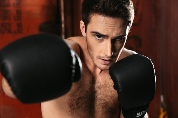 Imagen de boxeador de pie en un gimnasio y posando con las manos.